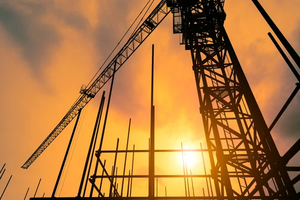 Industrial construction cranes and building silhouettes over sun at sunrise. — Stock Photo, Image