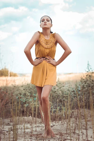 Beautiful dark-skinned brunette girl standing in a field — Stockfoto