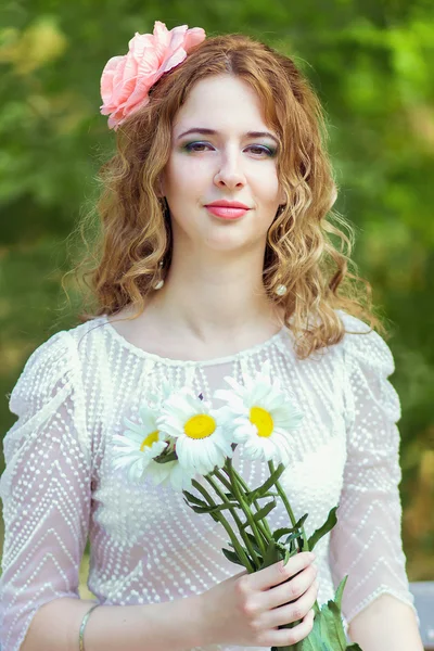 Jeune belle femme avec un bouquet de marguerites dans le parc — Photo