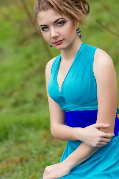 Potret wanita berambut coklat muda yang cantik dengan rambut indah dan riasan profesional dalam gaun biru panjang dengan irisan tinggi — Stok Foto