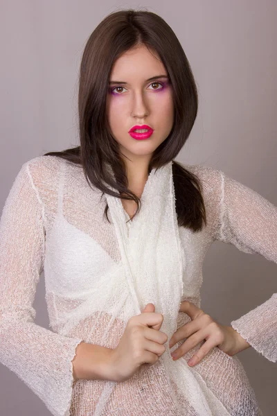 Studio emotional portrait of a beautiful young brunette woman with pink lips, wearing a white blouse — Stock Photo, Image