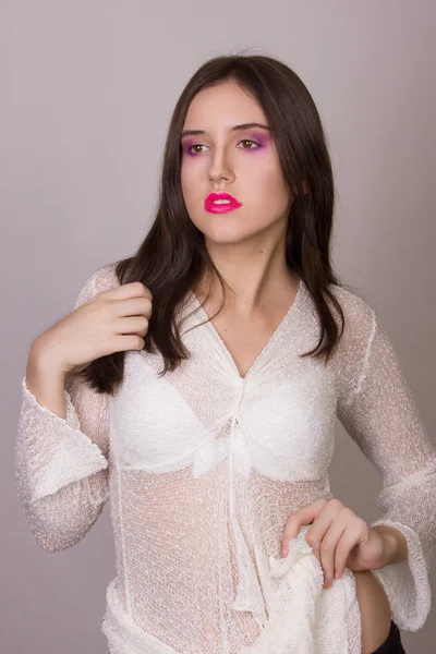 Студійний емоційний портрет красивої молодої брюнетки з рожевими губами в білій блузці — стокове фото