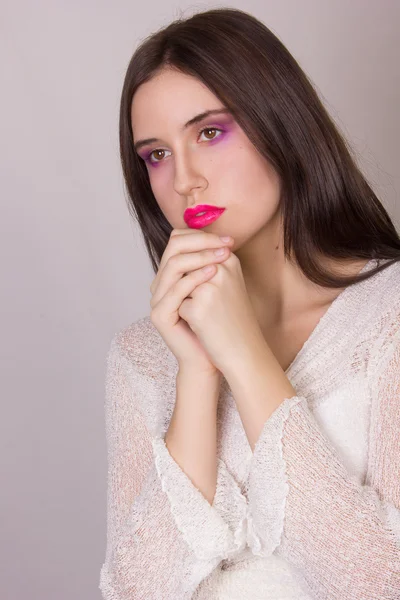 Studio emotional portrait of a beautiful young brunette woman with pink lips, wearing a white blouse — Stock Photo, Image