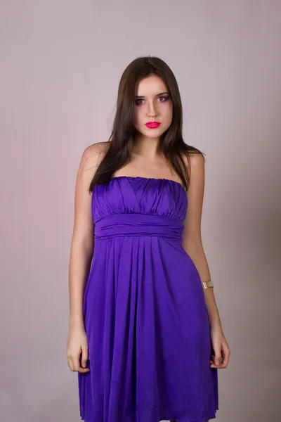 Emotional studio portrait of a beautiful brunette girl in a cocktail dress and lilac bright evening makeup with pink lips — Stock Photo, Image