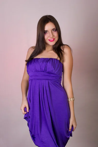 Emotional studio portrait of a beautiful brunette girl in a cocktail dress and lilac bright evening makeup with pink lips — Stock Photo, Image
