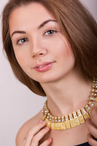 Portrait de belle jeune femme aux cheveux bruns sans maquillage dans un collier avec des pierres jaunes — Photo