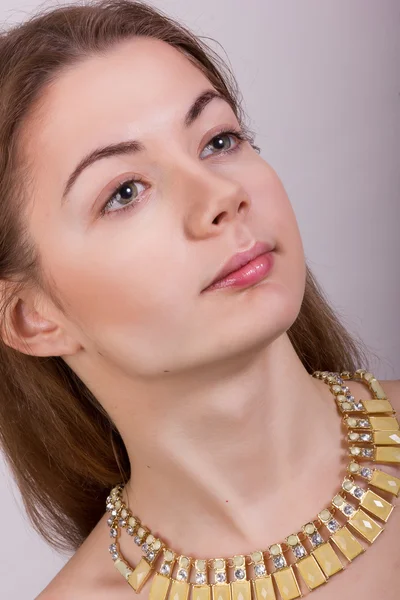 Portrait de belle jeune femme aux cheveux bruns sans maquillage dans un collier avec des pierres jaunes — Photo