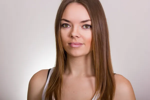 Портрет красивой молодой женщины в белой футболке с натуральным макияжем и прямыми каштановыми волосами — стоковое фото