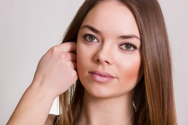 Retrato de uma bela jovem mulher em uma camiseta branca com maquiagem natural e cabelo castanho liso — Fotografia de Stock