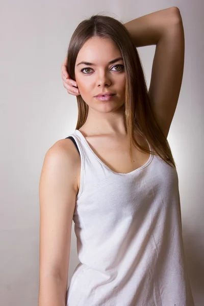 Retrato de una hermosa joven en una camiseta blanca con maquillaje natural y cabello castaño liso — Foto de Stock
