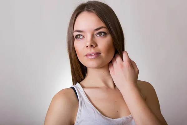 Retrato de una hermosa joven en una camiseta blanca con maquillaje natural y cabello castaño liso — Foto de Stock