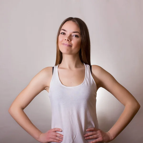 Retrato de uma bela jovem mulher em uma camiseta branca com maquiagem natural e cabelo castanho liso — Fotografia de Stock