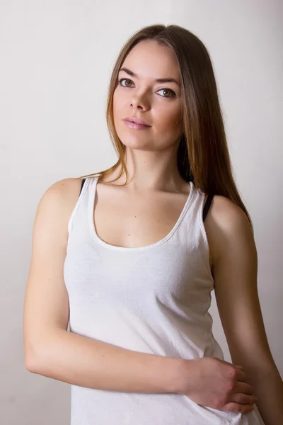 Retrato de uma bela jovem mulher em uma camiseta branca com maquiagem natural e cabelo castanho liso — Fotografia de Stock