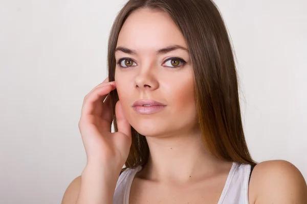 Portret van een mooie jonge vrouw in een wit t-shirt met natuurlijke make-up en rechtstreeks bruin haar — Stockfoto