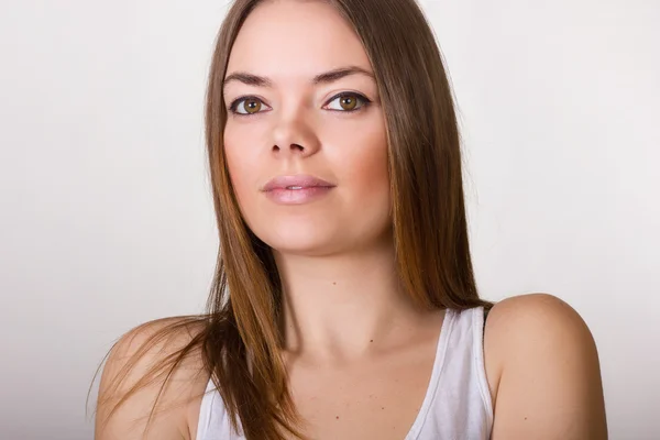 Retrato de uma bela jovem mulher em uma camiseta branca com maquiagem natural e cabelo castanho liso — Fotografia de Stock