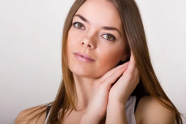 Portret van een mooie jonge vrouw in een wit t-shirt met natuurlijke make-up en rechtstreeks bruin haar — Stockfoto