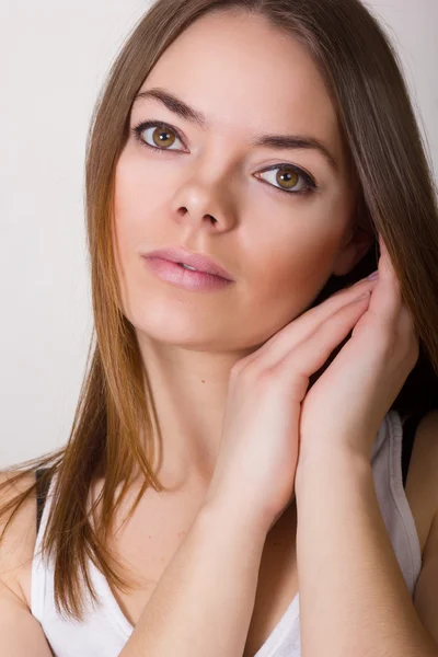 Retrato de uma bela jovem mulher em uma camiseta branca com maquiagem natural e cabelo castanho liso — Fotografia de Stock