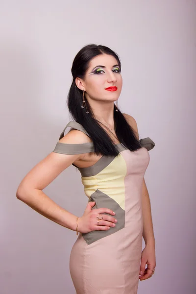 Portrait of beautiful young brunette woman in studio with bright evening make-up in a short beige dress — Stock Photo, Image