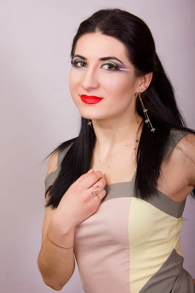 Portrait of beautiful young brunette woman in studio with bright evening make-up in a short beige dress — Stock Photo, Image