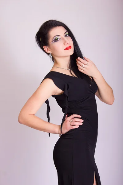 Mooie slanke jonge brunette vrouw in avond zwarte jurk en sieraden — Stockfoto