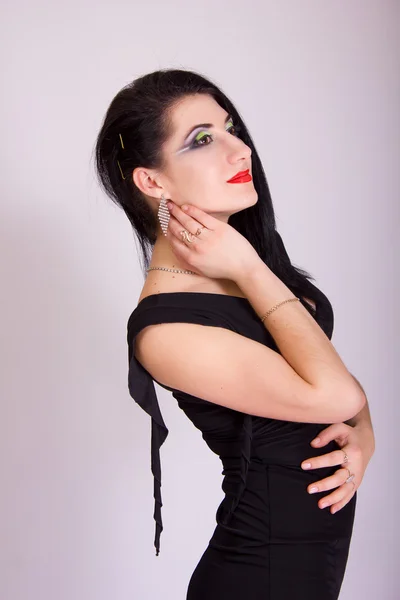 Schöne schlanke junge brünette Frau in schwarzem Abendkleid und Schmuck — Stockfoto