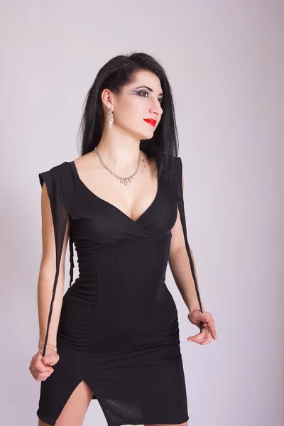 Bella sottile giovane donna bruna in abito da sera nero e gioielli — Foto Stock