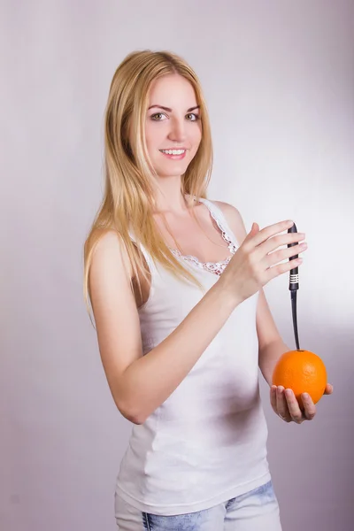 Hermosa joven rubia posando sobre un fondo blanco en el estudio con una naranja en las manos —  Fotos de Stock