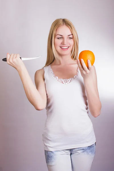 Piękna Młoda blondynka pozowanie na białym tle w studio z pomarańczy w ręce — Zdjęcie stockowe