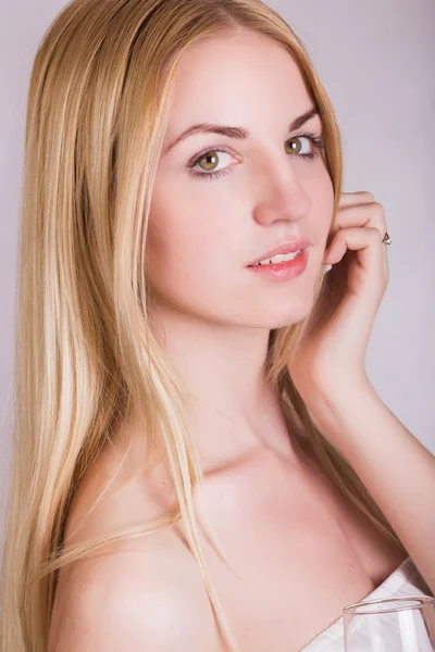 Retrato de uma bela jovem loira em um fundo branco em um vestido branco curto com renda preta. Menina bonito posando com uma taça de champanhe em suas mãos . — Fotografia de Stock