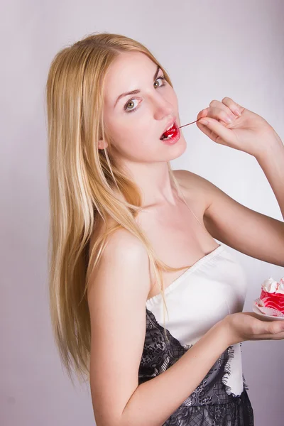 Portret van een mooie jonge blonde vrouw in de studio op een witte achtergrond. meisje poseren in een mooie jurk met een taart in de vorm van hart. — Stockfoto