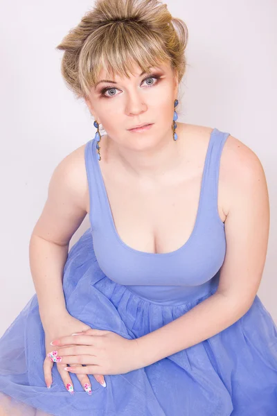 Portrait of a beautiful young blonde woman with short hair and dressed in a blue short dress. Girl posing with different emotions in the studio. — Stock Photo, Image