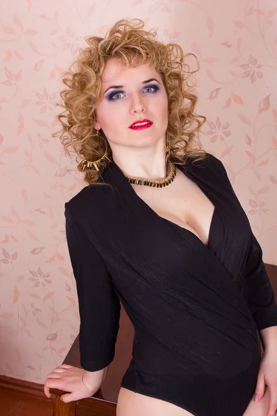 Portrait of a beautiful young blonde woman in a retro style. Girl dressed in a black bodysuit, shows emotion — Stock Photo, Image