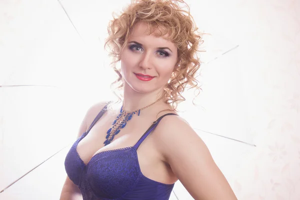 Portrait of a beautiful young blonde woman in lingerie. Girl with curly hair posing on a beautiful background indoors — Stock Photo, Image