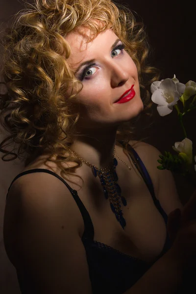 Portrait of a beautiful young blonde woman with curly hair in lingerie posing in the shadows — Stock Photo, Image