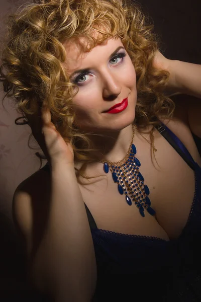 Portrait of a beautiful young blonde woman with curly hair in lingerie posing in the shadows — Stock Photo, Image