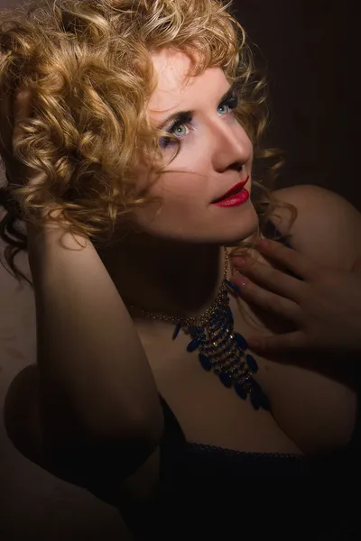 Portrait of a beautiful young blonde woman with curly hair in lingerie posing in the shadows — Stock Photo, Image