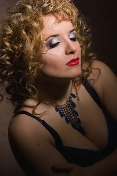 Portrait of a beautiful young blonde woman with curly hair in lingerie posing in the shadows — Stock Photo, Image