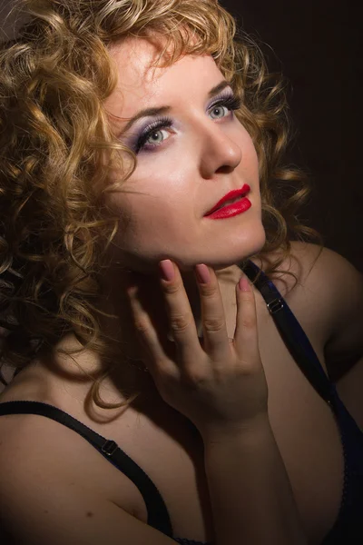 Portrait of a beautiful young blonde woman with curly hair in lingerie posing in the shadows — Stock Photo, Image