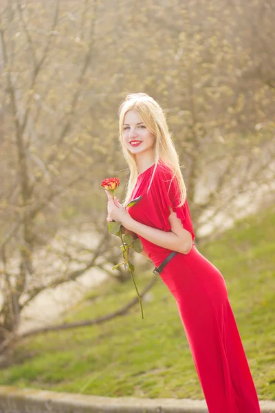 Portret van blonde vrouw in rood maxi jurk buiten — Stockfoto