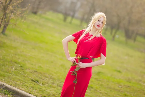 Portret van blonde vrouw in rood maxi jurk buiten — Stockfoto