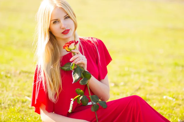 Portret van blonde vrouw in rood maxi jurk buiten — Stockfoto