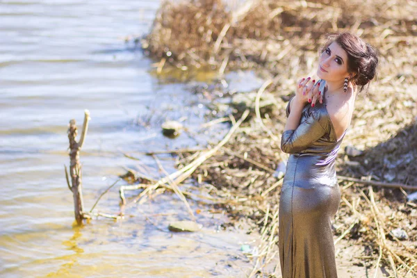 Donna di lusso in un lungo abito da sera nero sulla spiaggia. Bella ragazza al mare . — Foto Stock