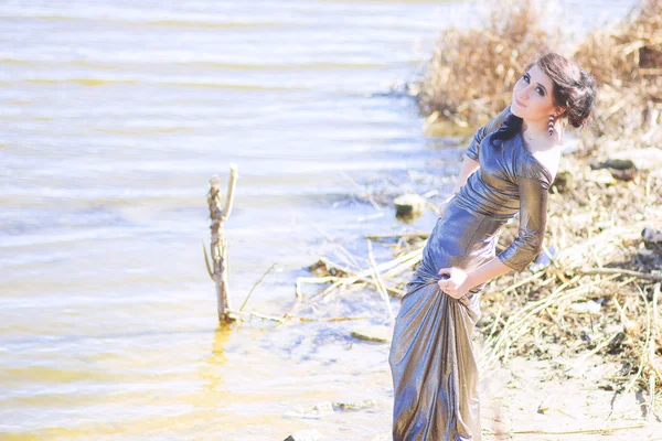 Donna di lusso in un lungo abito da sera nero sulla spiaggia. Bella ragazza al mare . — Foto Stock