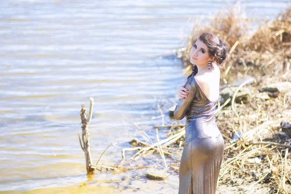 Donna di lusso in un lungo abito da sera nero sulla spiaggia. Bella ragazza al mare . — Foto Stock