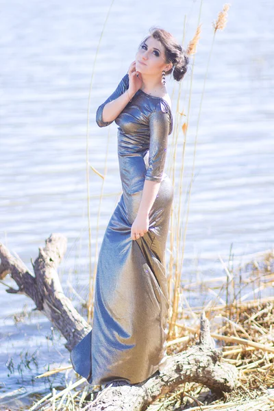 Luxury woman in a long black evening dress on the beach. Beautiful young girl at the sea. — Stock Photo, Image