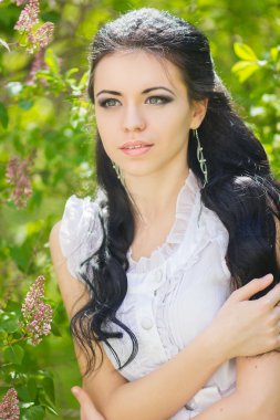 güzel genç esmer doğada poz. saç ve makyaj romantik beyaz elbiseli kız