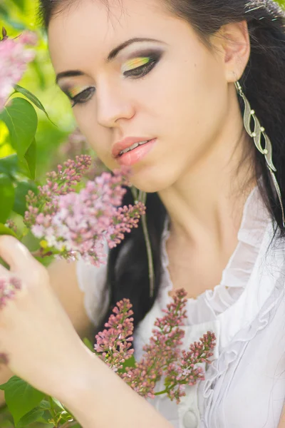 Hermosa joven morena posando en la naturaleza. Chica con pelo y maquillaje en vestido romántico blanco — Foto de Stock