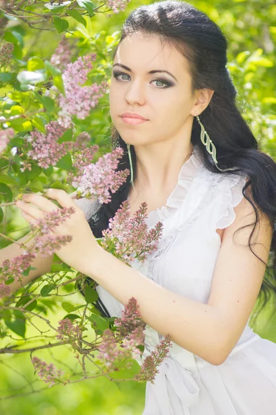 Belle jeune brune posant dans la nature. Fille avec les cheveux et le maquillage en robe romantique blanche — Photo