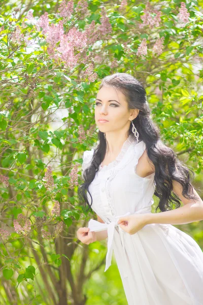 Beautiful young brunette posing in nature. Girl with hair and makeup in white romantic dress — Stock Photo, Image