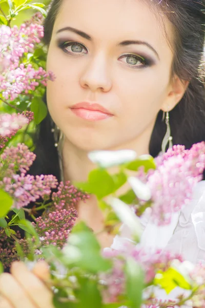 Bella giovane bruna in posa nella natura. Ragazza con capelli e trucco in abito romantico bianco — Foto Stock